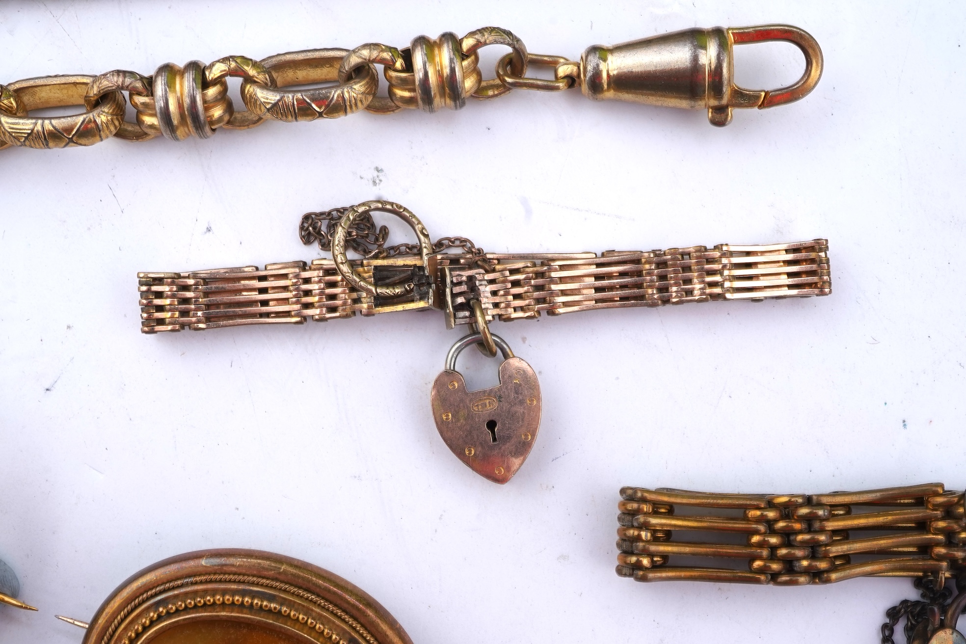 A group of gilt metal/pinchbeck jewels, 19th and early 20th century, comprising: a brooch of knotted design; two gate bracelets; a fancy link bracelet; an open-faced pocket watch; two oval panel brooches, and two watch c